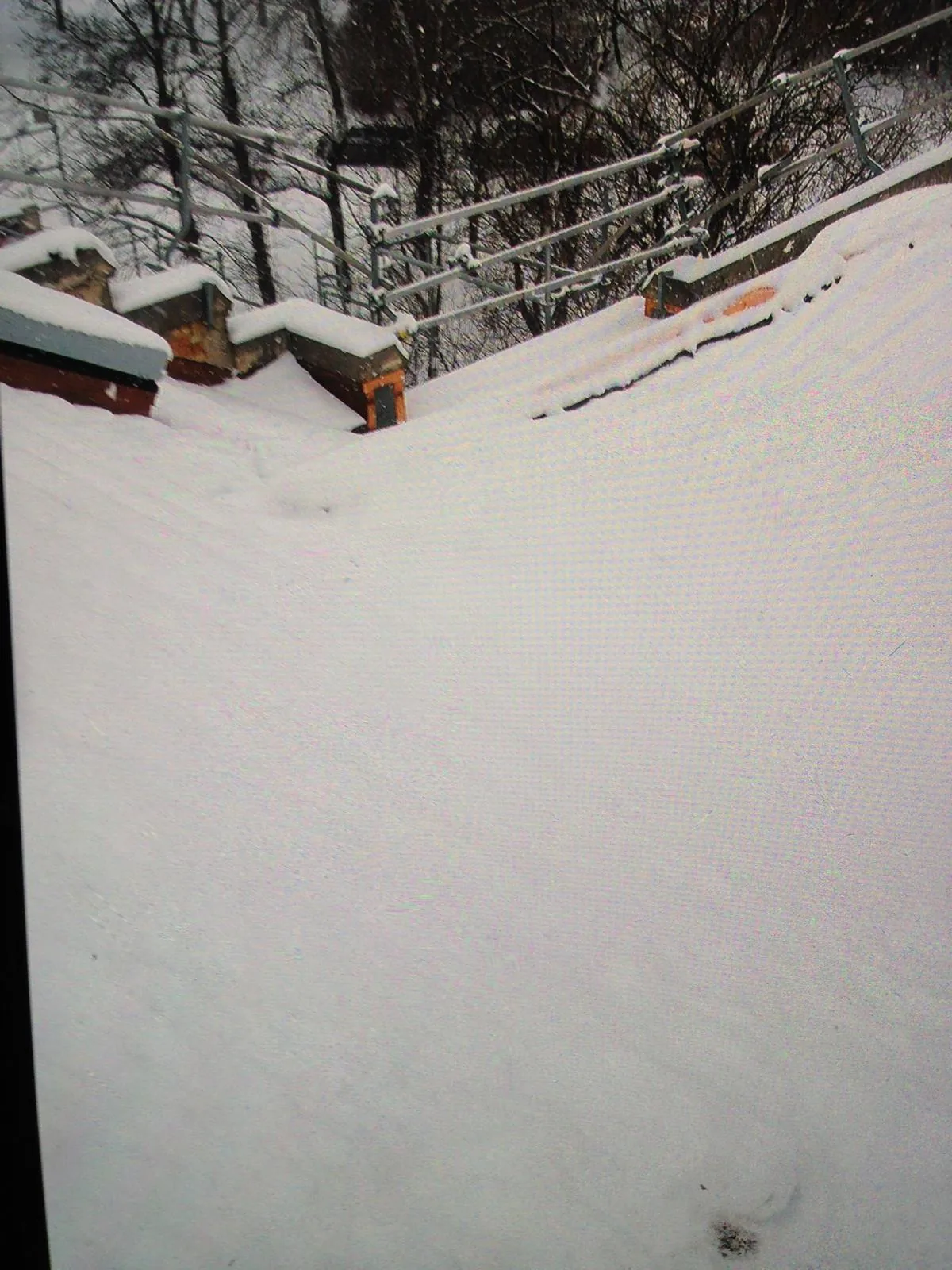 Deep snow drift banked up against a roofline and chimney stacks in Edmonton