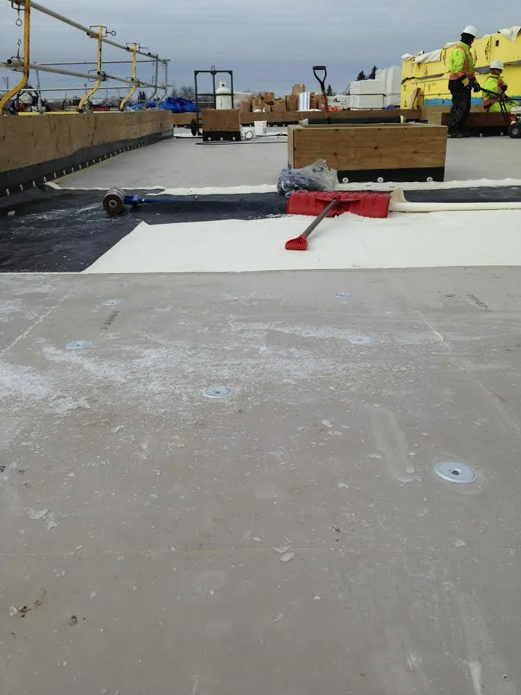 Flat roof membrane and insulation work in progress with roofing crew