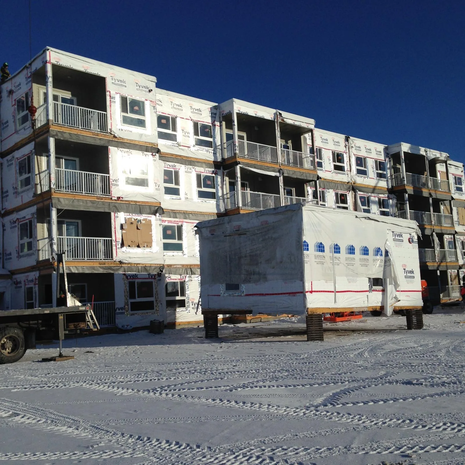 Multi-storey building under construction wrapped in Tyvek weather barrier in the snow