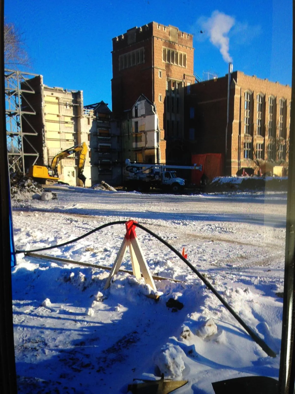 Commercial construction and demolition site with excavator and historic brick building